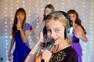 Group of happy girls singing on karaoke