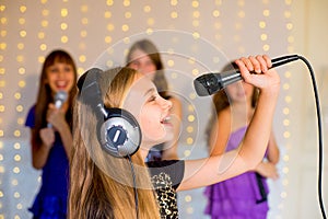 Group of happy girls singing on karaoke