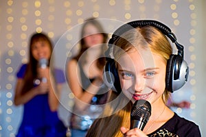 Group of happy girls singing on karaoke