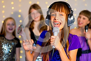 Group of happy girls singing on karaoke