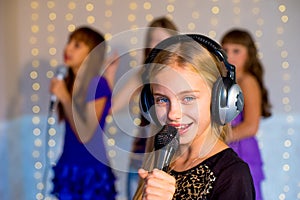 Group of happy girls singing on karaoke