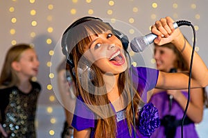 Group of happy girls singing on karaoke