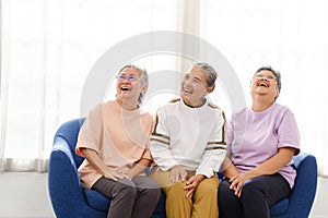 The group of happy and healthy three Asian senior women sits together on a sofa. Smiling and laughing together