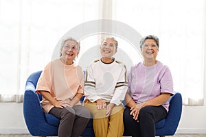 The group of happy and healthy three Asian senior women sits together on a sofa. Smiling and laughing together