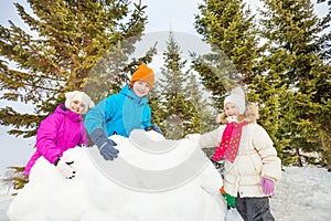 Group of happy kids build behind snow wall