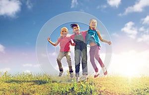 Group of happy kids jumping high on green field