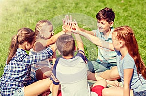 Group of happy kids making high five outdoors