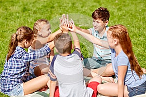 Group of happy kids making high five outdoors