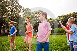 Group of happy kids playing games on green field outdoors