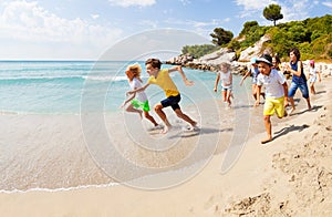 Group of happy kids racing on sandy beach