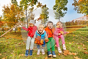 Group of happy kids sit on hammock and enjoy it