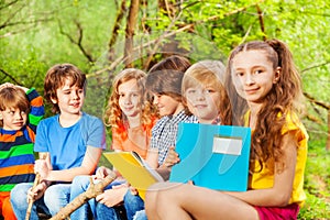 Group of happy kids sitting with books in the park