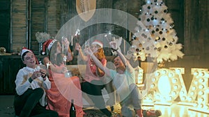 Group of happy laughing friends raising hands near Christmas tree. Christmas celebration party.