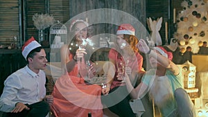 Group of happy laughing friends raising hands near Christmas tree. Christmas celebration party.