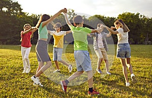 Group of happy little children playing games, dancing and having fun in the park