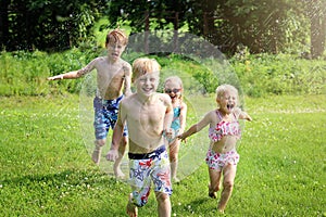 A Group of Happy Little Kids is Smiling as they Run Through the Sprinkler Outside on a Summer Day