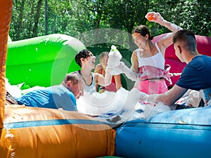 Group of happy men and women swimming in foam pool in adventure park