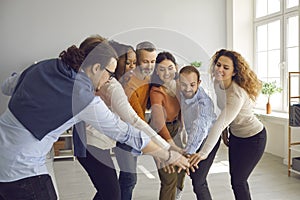 Group of happy motivated diverse business people joining hands in office meeting