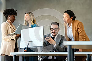 Group of happy multiethnic business people in formal wear gathered around computer in office