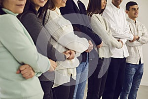 Group of happy multiethnic men and women standing close together and holding hands