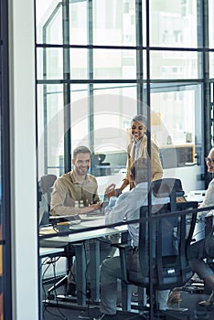 Group of happy multiracial business people sitting in board room in the modern office and discussing something while