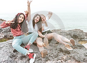 Group of happy multiracial female tourists having fun and smiling - Best friends enjoy their vacation while relaxing sitting on