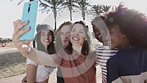 Group of happy multiracial people taking a selfie with mobile phone outdoors