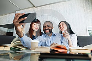 Group of happy multiracial young friends sitting at the cafe after classes or work and relaxing on coffee break with