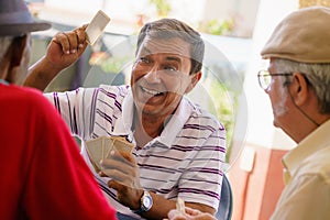 Group Of Happy Old Friends Playing Cards And Laughing