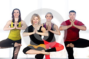 Group of happy people doing yoga training in class