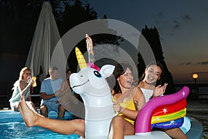 Group of happy people enjoying fun pool party in evening