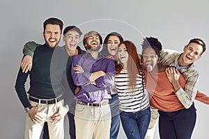 Group of a happy people friends hugging indoors and looking cheerful at camera.