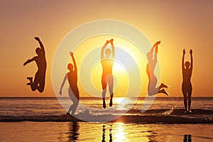Group of happy people jumping in the sea at sunset
