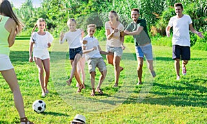 Group of happy people with kids outdoors playing football