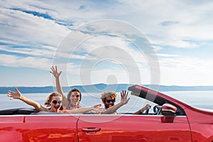 Group of happy people in red convertible car.