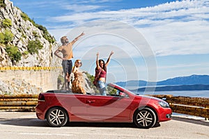 Group of happy people in red convertible car.