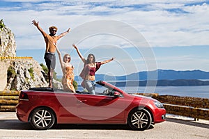Group of happy people in red convertible car