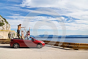 Group of happy people in red convertible car