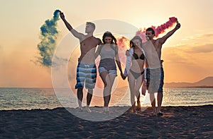 Group of happy people walking on beautiful beach in summer sunset