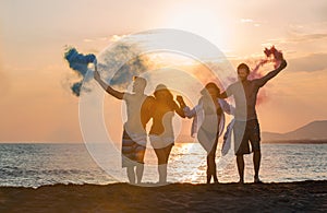 Group of happy people walking on beautiful beach in summer sunset