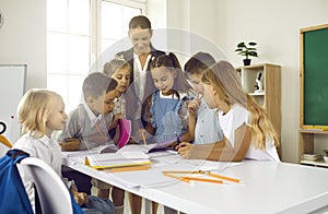 Group of happy school children with their teacher having lesson in the classroom