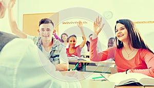 Group of happy school pupils raise their hands up