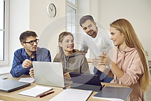 Group of happy university students discussing something while working on project together