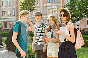 Group of happy teenagers 13, 14 years walking along the city street, friends greet each other at a meeting.
