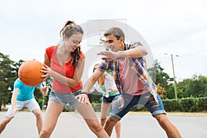 Group of happy teenagers playing basketball