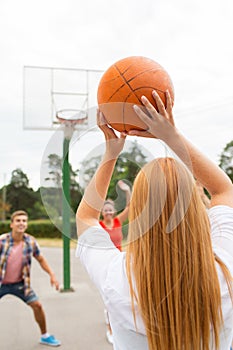 Group of happy teenagers playing basketball