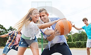 Group of happy teenagers playing basketball