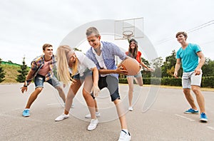 Group of happy teenagers playing basketball