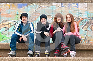 Group of happy teenagers in roller skates sitting