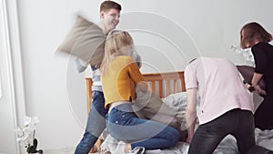 Group of happy teenegers fighting pillows in room